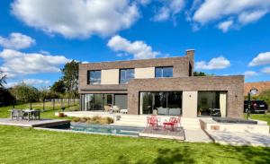 Maison cubique en briques brunes. Façade jardin et piscine.